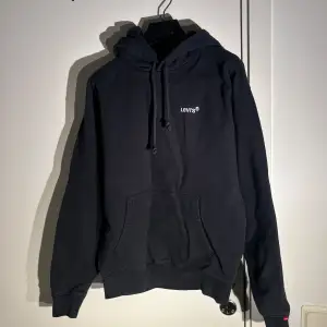 Säljer en svart hoodie från Levi's i bra skick. Den har en klassisk design med en känguruficka och justerbar huva. Perfekt för höst och vinter, och passar till både chill och casual outfits. Storleken är normal och materialet är mjukt och bekvämt.