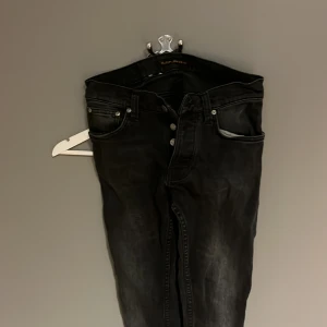 Svarta jeans från Nudie Jeans Grim trim - Säljer ett par svarta jeans från Nudie Jeans i bra skick. De har en snygg tvättad look och klassisk femficksdesign. Perfekta för både vardag och fest! Passar till allt och är superbekväma. Hör av dig om du är intresserad! 🖤