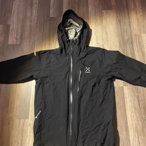 Haglöfs vindjacka - Säljer en felfri vindjacka från Haglöfs med huva och dragkedja. Perfekt för blåsiga dagar. Jackan har långa ärmar och är tillverkad i ett slitstarkt material. S i kvinnostorlek. Sitter perfekt på mig som är 174cm lång.