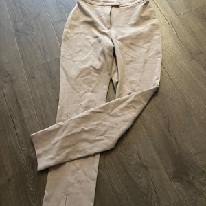 Beige byxor från NA-KD - Snygga beige byxor från NA-KD med en stilren design. Byxorna har en rak passform och är perfekta för en chic look. De är tillverkade i ett mjukt material som ger en bekväm känsla hela dagen.