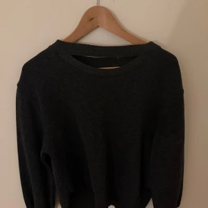Mörkgrå tröja från Zara - Säljer en stilren mörkgrå tröja från Zara. Tröjan har en rund halsringning och långa ärmar. Perfekt för en avslappnad look. Tillverkad i ett mjukt material som känns skönt mot huden.