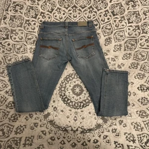 Blå jeans från Nudie Jeans - Snygga blå jeans från Nudie Jeans med klassisk design  orange De har en normal passform och är perfekta för en avslappnad stil. Märkeslogga på bakfickan ger en extra touch.