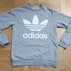 Grå sweatshirt från Adidas - Säljer en grå sweatshirt Adidas. Tröjan har långa ärmar och en rund halsringning. Strl 176 (Xs-S)