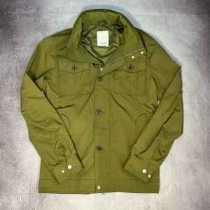 J.Lindeberg Field jacket  - Säljer denna feta olivgröna Field jacket från J.Lindeberg för bara 1599kr! Skick 10/10 utan defekt, fläckar eller tecken på användning. Storlek M.