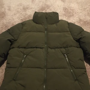 Ny med prislapp Olivgrön pufferjacka xs  från  Hm - Säljer en olivgrön pufferjacka. Jackan har en hög krage och dragkedja framtill. Den är vadderad och perfekt för kyligare dagar. Två snedställda fickor med dragkedja ger extra funktionalitet. En stilren och praktisk jacka för vintern.