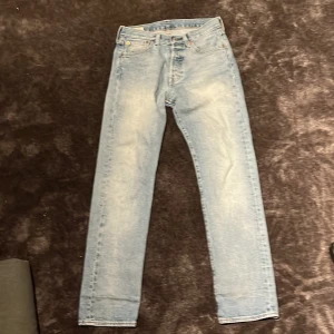 Ljusblå Levis 501 jeans - Säljer ett par klassiska ljusblå Levis 501 jeans. De har en rak passform och är tillverkade i denim. Perfekta för en avslappnad stil. Jeansens ikoniska design gör dem tidlösa och lätta att matcha med olika outfits.