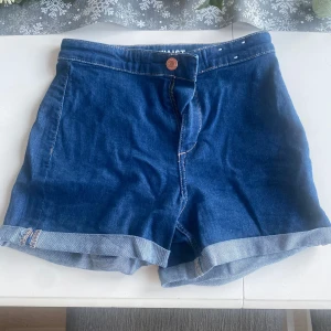 &Denim jeansshorts - Snygga blå jeansshorts med knapp och dragkedja framtill. De har en klassisk design med uppvikta benslut och är perfekta för en avslappnad stil. Passar utmärkt till varma sommardagar.