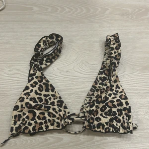 Leopardmönstrad bikiniöverdel - Oanvänd .Trendig leopardmönstrad bikiniöverdel med knytband. Perfekt för en djärv look på stranden. Justerbara band för bästa passform.