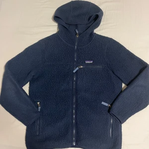 Blå fleecetröja från Patagonia - Säljer en snygg blå fleecejacka från Patagonia med huva och dragkedja. Strl M men sitter som S