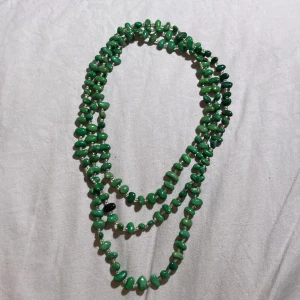 Grönt halsband med pärlor - Långt halsband med bönformade gröna pärlor och små genomskinliga pärlor.