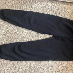 Svarta mjukisbyxor från Andy by Ellen Tracy - Säljer ett par svarta mjukisbyxor från Andy by Ellen Tracy. Byxorna har en bekväm passform med elastisk midja och är perfekta för en avslappnad stil. De är tillverkade i ett mjukt material som gör dem sköna att bära. Använd bara 1 gång.