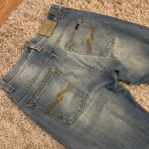 Nudie Jeans  - Nudie Jeans med klassisk femficksdesign och broderade detaljer på bakfickorna. De har en straight passform och är tillverkade i slitstarkt denim. Perfekta för en avslappnad stil. Riktigt snygg wash på dem, mjuka i materialet och mycket bra skick utan några skavanker. Storlek 30/32. Fraktas antigen samma dag som köp eller dagen därpå🙌💯
