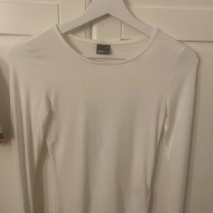 Vit långärmad topp från Gina Tricot - Säljer en stilren vit långärmad topp från Gina Tricot. Perfekt basplagg med rund halsringning, tillverkad i ett mjukt och bekvämt material. Passar utmärkt till olika outfits och tillfällen. Nära passform och i storlek XS Soft touch serien och i nyskick!🤝