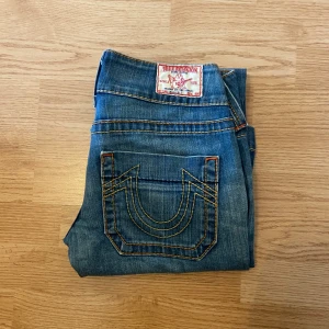 True Religion Jeans Bootcut Flare - !skicka bud för snabb affär! True religion jeans, Bootcut lågmidjade. Storlek 27 i bra skick men lite heeldrag. Mått:                                                             Midja 36cm Ytterben 96cm Innerben 76cm Ben öppning 24,5cm
