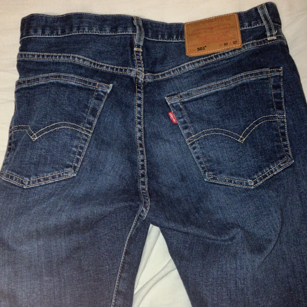 Klassiska Levis 501 jeans i en snygg blå färg. De har en rak passform och är tillverkade i slitstarkt denim. Byxorna har knappgylf och fem fickor.. Farkut & Housut.