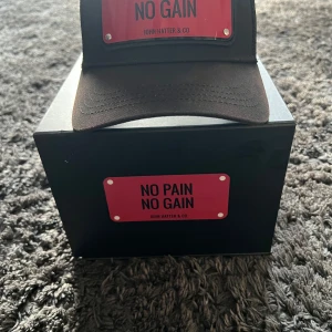 Keps från John hatter svart/No Pain No Gain - Säljer en John hatter keps svet no pain no gain. Kepsen är i bra skick men man kan se framme på kepsen att den är använd Box ingår.PRIS kan diskuteras 