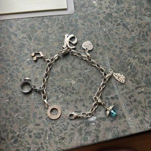 Charmarmband med berlocker i äkta silver - Äkta silvrigt armband med flera berlocker. Armbandet har en kedja i silverfärg. Perfekt för att ge en personlig touch. 