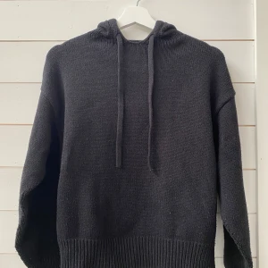 Svart stickad hoodie från Zara - Säljer en stilren svart stickad hoodie från Zara. Den har en klassisk design med långa ärmar och en bekväm huva med dragsko. Perfekt för kyligare dagar och ger en avslappnad look.