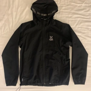 Svart vindjacka från Haglöfs - Säljer en svart vindjacka från Haglöfs med dragkedja och huva. Jackan har elastiska muddar vid ärmslut och nederkant. Köpte den för 2300 kr på en dansk sida. Passar även mig som har Xs/S i kläder☺️
