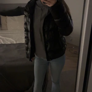 Svart pufferjacka - Säljer en svart pufferjacka med dragkedja från Superdry. Jackan har en glansig yta och långa ärmar, perfekt för kyligare dagar. Den är stilren och enkel att matcha med olika outfits. Finns inget tecken på bruk.