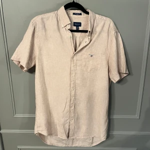 Beige linneskjorta från GANT - Säljer en stilren beige kortärmad linneskjorta från GANT.  Använd fåtal gånger. Strl M 39/40