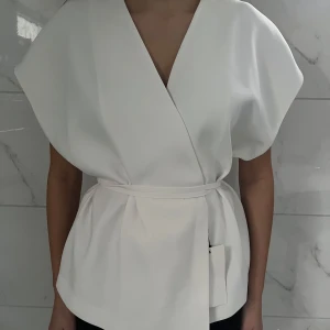 Omlottopp Med Knytning - Säljer nu denna fina slutsålda topp från Zara i storlek S. Jättefin topp med prislapp kvar men pga storleken så är den för stor för mig. Det finns två knappar som man knäpper toppen (är som en kofta) sedan snörning som man knyter runt midjan. Nypris 559! PRIS GÅR ATT DISKUTERA!! 🤗