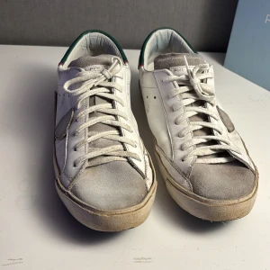 Vita sneakers från Philippe Model - Säljer just nu ett par vita philippe model skor med gröna detaljer. Har inte använt dem så himla länge men det är bra skick på dem fortfarande. Storlek 42. Sköna och avslappnade skor att använda. Skriv om det är några frågor. 