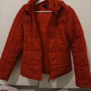 Röd quiltad jacka från H&M - Säljer en snygg röd quiltad jacka från H&M i storlek XS. Jackan har en dragkedja framtill och en mysig huva. Perfekt för kyliga dagar och ger en cool look med sin quiltade design.