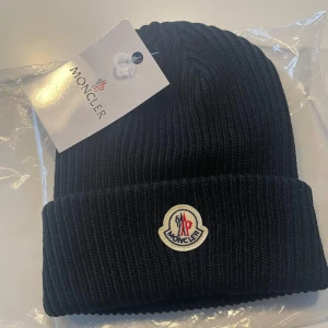 Svart ribbad mössa från Moncler - En svart och bekväm mössa från moncler. Priset är inte hugget i sten.
