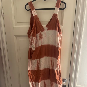 Orange och vit klänning från Zara - Snygg långklänning från Zara i orange och vitt med tie-dye mönster. Klänningen har en v-ringad design och breda axelband. Perfekt för en avslappnad sommarlook. 🌞