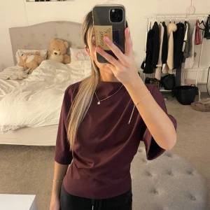 Vinröd topp med trekvartsärm - Säljer en stilren vinröd topp med trekvartsärm. Perfekt för en elegant look. Toppen har en mjuk och bekväm passform.