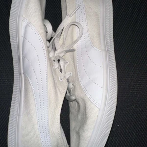 Vita sneakers från Puma - Säljer ett par vita sneakers från Puma med klassisk design och snörning. Skorna har en vit sula och Puma-loggan på hälen. Perfekta för en avslappnad stil.