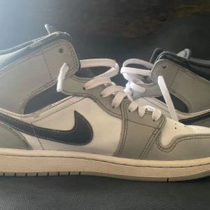 Air Jordan 1 Mid Light Smoke Grey Anthracite - Säljer ett par stilrena Nike Air Jordans 1 mid i grått och vitt. Skorna är köpta på Soleplus för 3.200kr och är i storlek 42. Säljer dom nu för dom e för små. Mitt pris 1.200kr