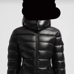 Svart moncler pufferjacka  - Säljer en snygg svart moncler som är helt ny och endast testat. Jackan har en glansig finish och dragkedja framtill. Perfekt för kalla dagar och håller dig varm och stilren. Den har långa ärmar och som sagt helt ny endast testat. Pris kan diskuteras! ❤️