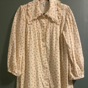 Blommig klänning från Edited - Charmig blommig klänning från Edited i ljusa toner. Den har långa ärmar och en söt volangkrage. Perfekt för vår och sommar med sitt lätta och luftiga material. Använt bara några gånger!