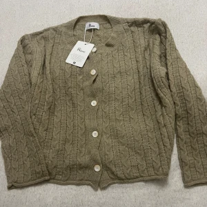 Koreansk stickad kofta  - Säljer en superfin beige stickad kofta från Sydkorea i storlek One Size. Men sitter som en S. Den har ett klassiskt flätmönster och knäpps med snygga vita knappar. Perfekt för höst och vinter, och den är i helt nytt skick. Passar både till vardags och lite finare tillfällen. 🧶✨