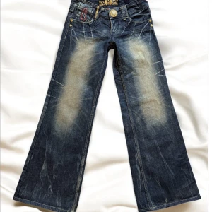 Mörkblå jeans från Riobera - Säljer ett par coola mörkblå jeans från Riobera med vintage-look. De har broderade detaljer och en unik knappdesign. Jeansen har en loose passform och är perfekta för en avslappnad stil. Bakfickorna har snygga broderier och dragkedjor som ger extra edge. Perfekta för höst och vår!