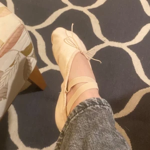Beige balettskor med resårband - Säljer ett par beige balettskor i mycket bra skick. De har resårband för bättre passform och en mjuk sula för smidiga rörelser. Perfekta för danslektioner!! Finns extra längd till fötterna  och är storlek i  38!!🌸🌸