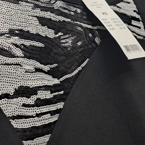 Svart klänning med paljettdetaljer - Snygg svart klänning i XS med coola silverfärgade paljettdetaljer på bröstet. Perfekt för en festkväll när du vill glittra lite extra. Klänningen har en tight passform och korta ärmar. Ett måste för garderoben om du älskar att sticka ut!