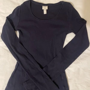 Mörkblå ribbad topp - Säljer en mörkblå ribbad topp i storlek S. Fint skick förutom den liten slitning som jag lagat. Sitter tight och är u-ringad.