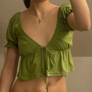 Grön croppad topp med knyt - Säljer en superfin grön croppad topp med korta puffärmar och knytning framtill. Köpt på sellpy men aldrig använd. Köp endast med bundle!!🎀
