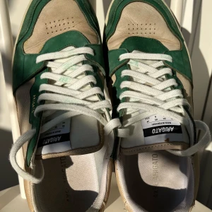 Axel Arigato sneakers i grönt och beige - Bilder samt förslag på text:  AXEL ARIGATO Sneakers  Väl använda men fortsvarande snygga sneakers i storlek 42.  Sulan är fin men men ovansidan i läder har slitits, se bilder.   Pris 500kr Nypris ca 2500kr