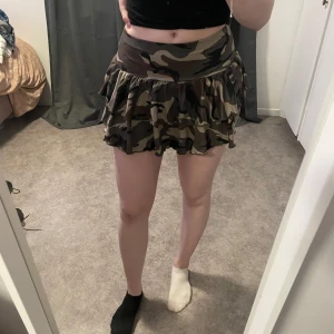 Camo kjol  - Säljer en supercool camouflage kjol. Den har en volangdetalj som ger en extra touch och är perfekt för en avslappnad stil. Kjolen är kort och passar perfekt för sommarens äventyr. Användes en gång på halloween 