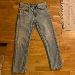 Ljusblå jeans från Nudie Jeans  - Ett par ljusblå jeans från Nudie Jeans i mycket bra skick. Den vita ”fläcken” på låret är ingen fläck utan fanns där när de köptes på kennedies. Modellen är gritty Jackson och är raka och medellösa i modellen. Storlek W30 L30
