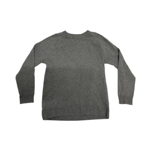 Grå stickad tröja - Mysig grå stickad tröja i normal passform. Perfekt för kyliga höst- och vinterdagar. Tröjan har långa ärmar och ribbade muddar vid ärmslut och nederkant för extra komfort. Ett måste i garderoben för en stilren och enkel look.