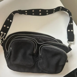 Svart axelväska från Gina Tricot - Snygg svart axelväska från Gina Tricot med flera dragkedjefickor för extra förvaring! Väskan har små hål vid baksidan, kan diskutera pris!