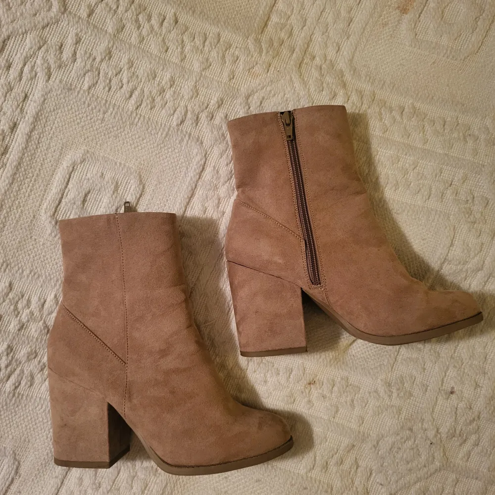 Snygga beige boots i fuskmocka med dragkedja på sidan. De har en stabil klack och är perfekta för alla säsonger. Skostorleken är dam 38. De är i nästan nyskick, endast använd en gång och redo för nya äventyr!. Skor.