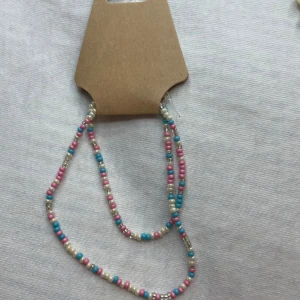 Färgglatt pärlhalsband - Säljer ett superfint halsband med små pärlor i rosa, blått och vitt. Perfekt för att liva upp vilken outfit som helst! Halsbandet är lätt och bekvämt att bära, och passar både till vardags och fest. Ett måste för dig som älskar färg och stil! 💖💙🤍