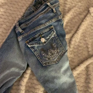 Blå jeans med broderade fickor - Säljer ett par blå jeans med broderade detaljer på bakfickorna. 