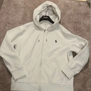  Ralph Lauren zip - Säljer en stilren vit hoodie från Polo Ralph Lauren i stolek S. Den är i bra skick 8/10 och nypris är 2200kr, kvitto finns och den är 100% äkta. Tveka inte på skriva vid frågor och annat.
